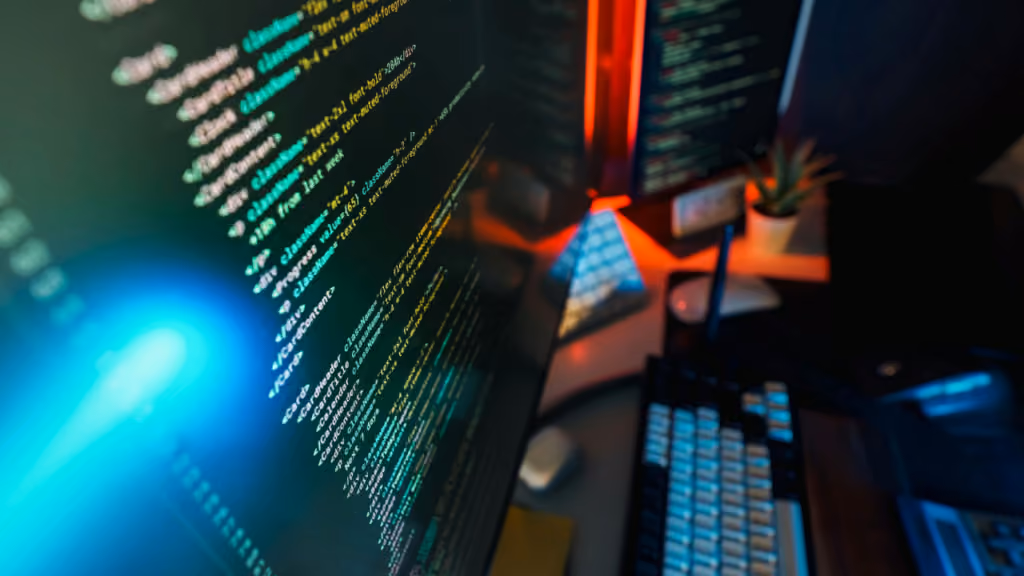 Écrans d’ordinateur affichant du code dans une pièce sombre