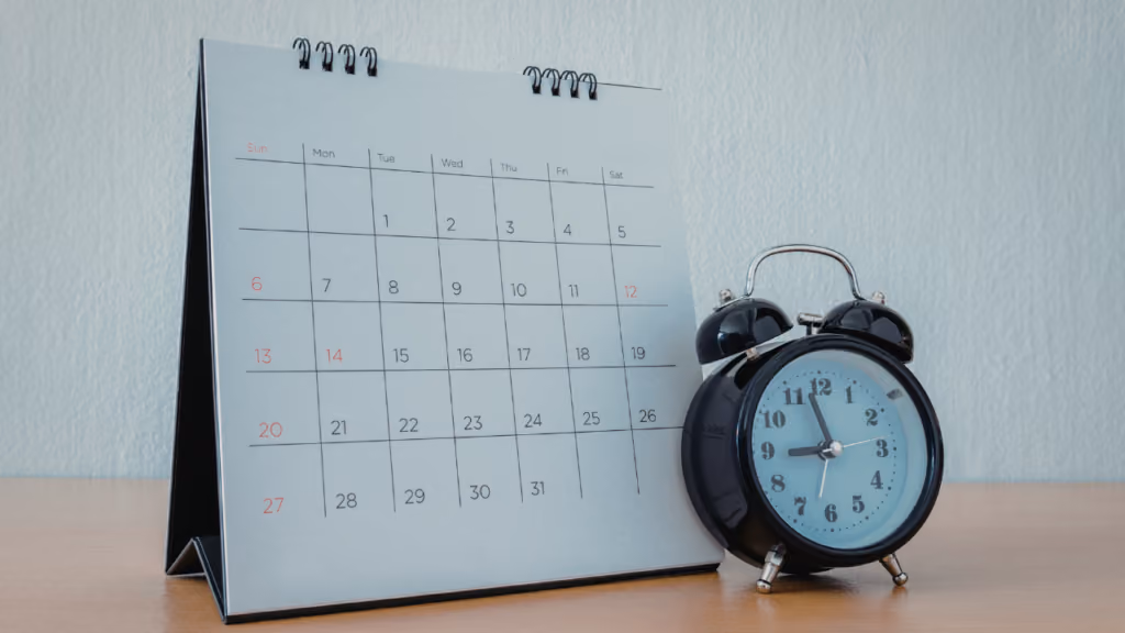 Calendrier mensuel posé à côté d’un réveil
